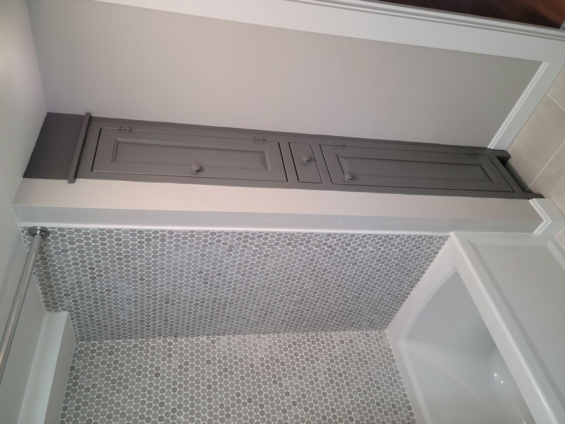 A bathroom with a gray cabinet above the bathtub.
