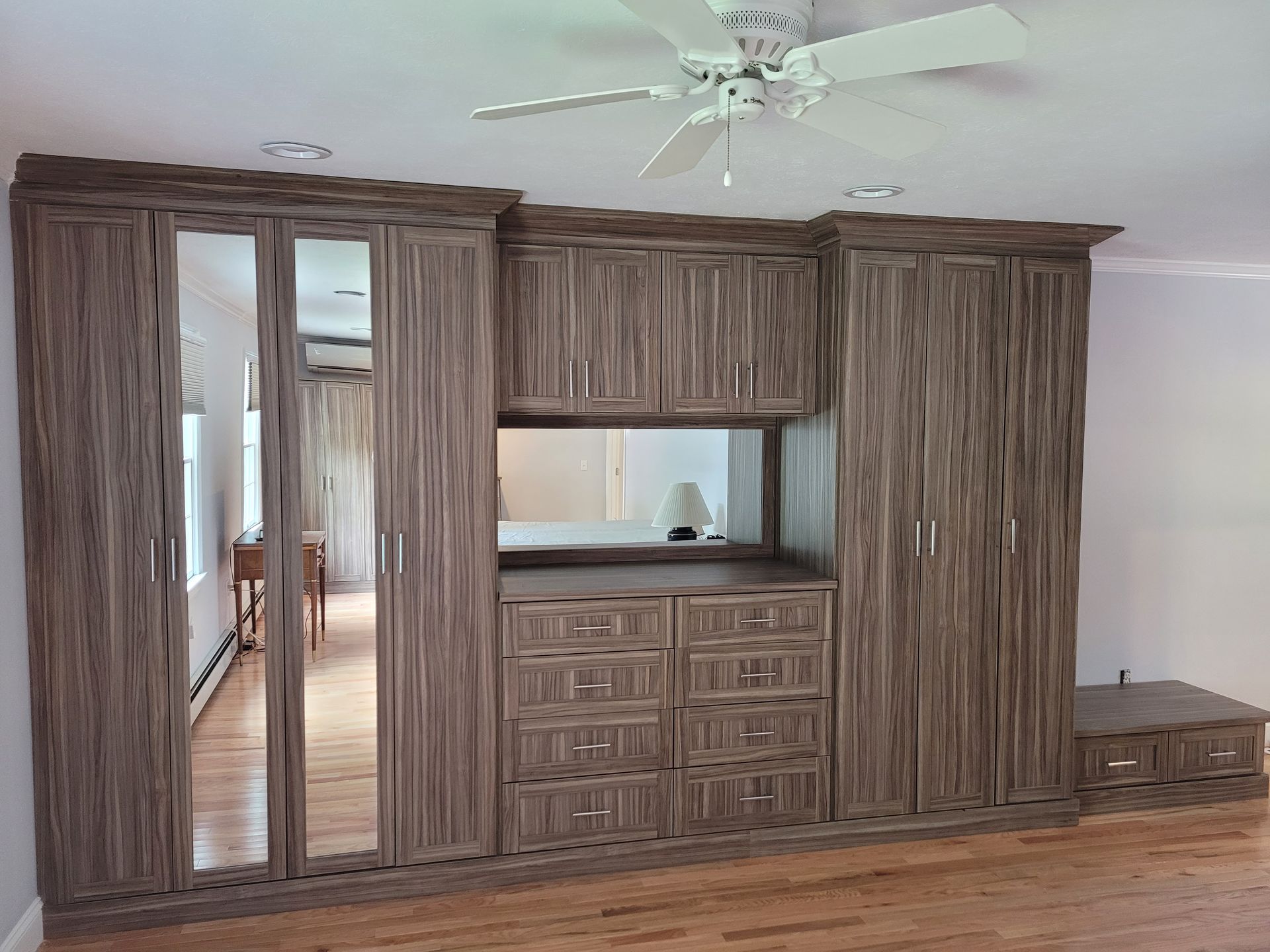 A bedroom with a lot of cabinets and a ceiling fan.