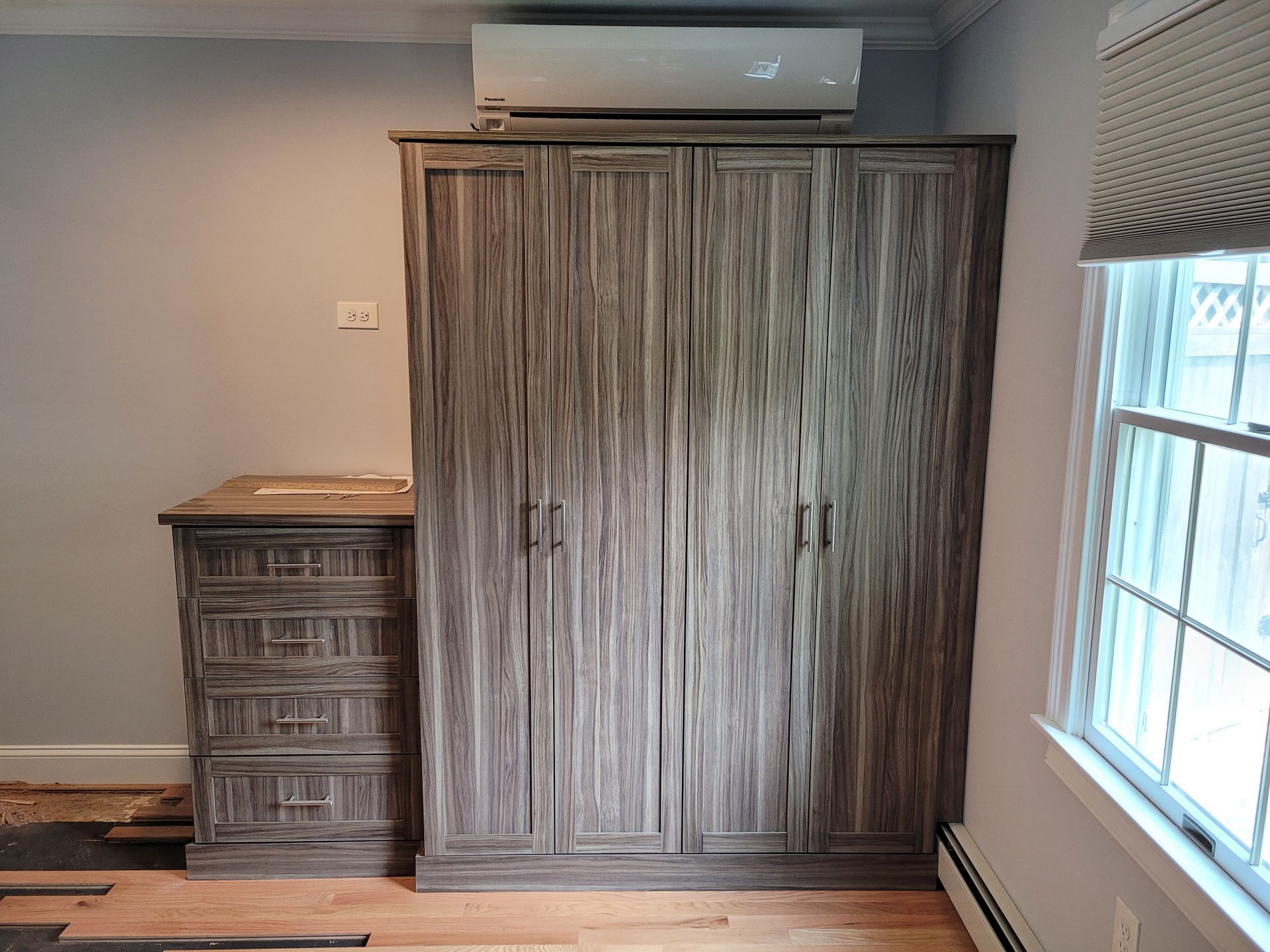 A bedroom with a large wooden wardrobe and a window.