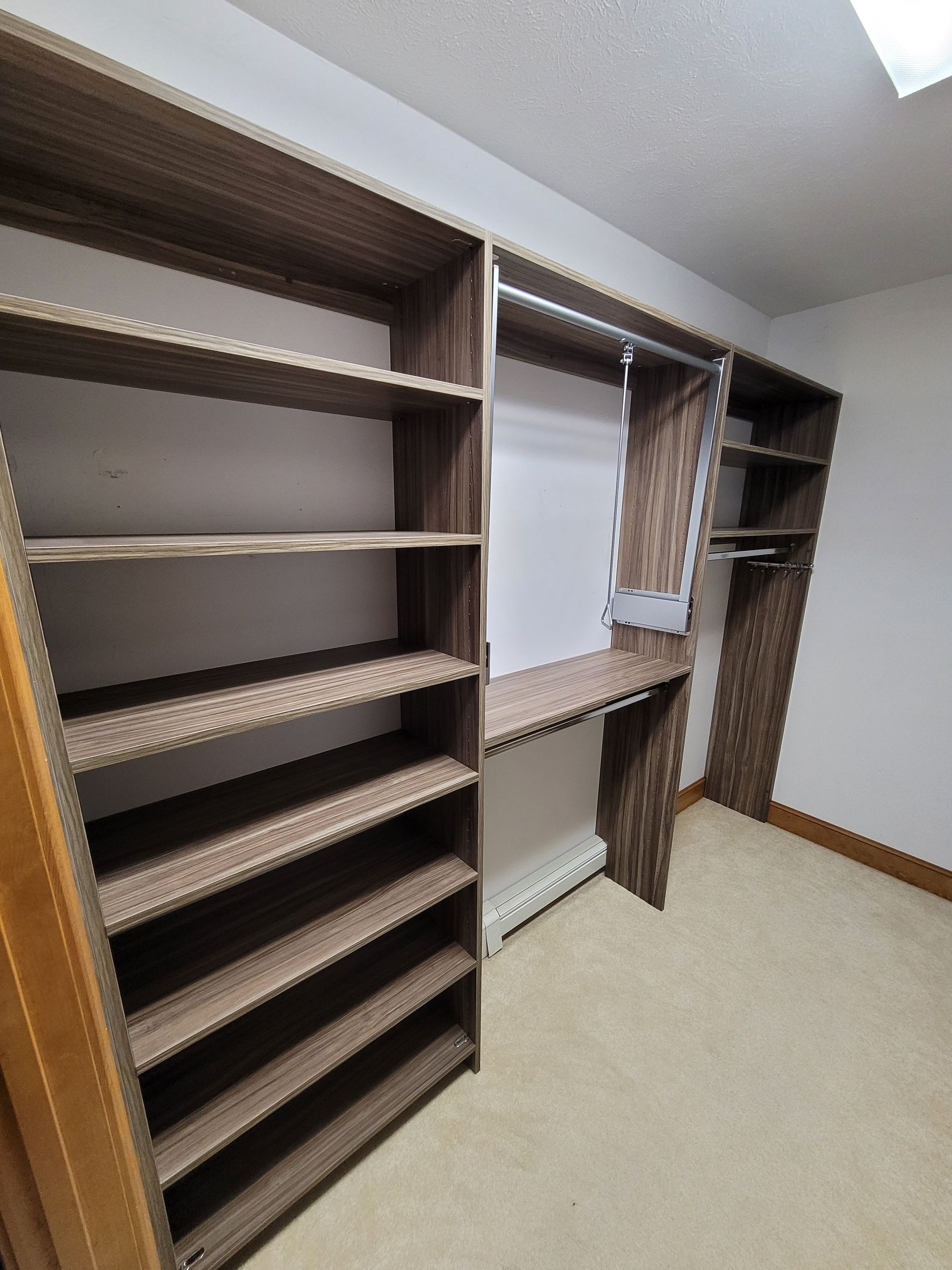 A walk in closet with lots of shelves and a desk.