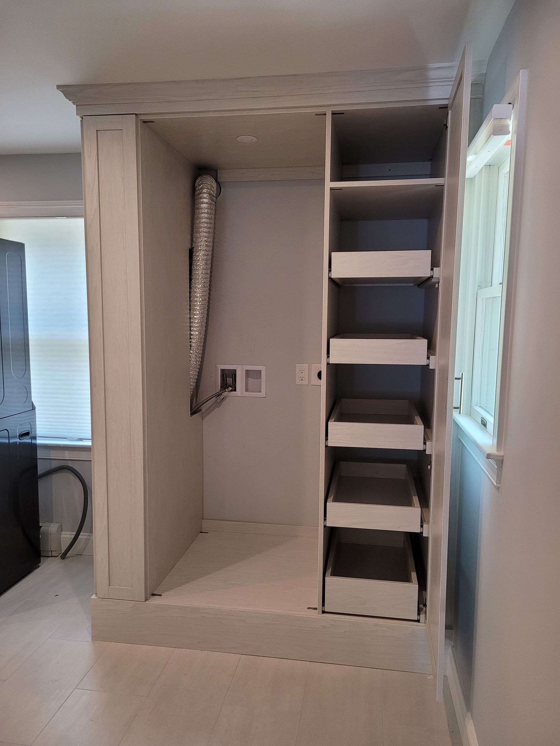 A closet with drawers and shelves in a room with a window.