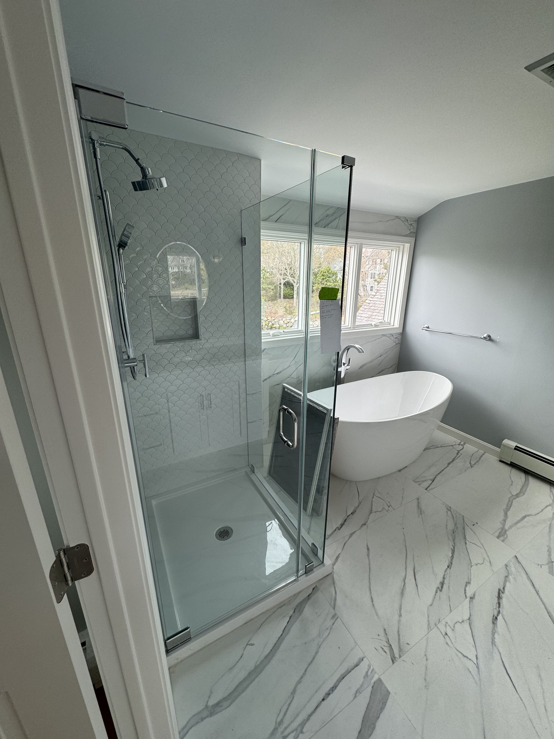 A bathroom with a tub , shower , and window.