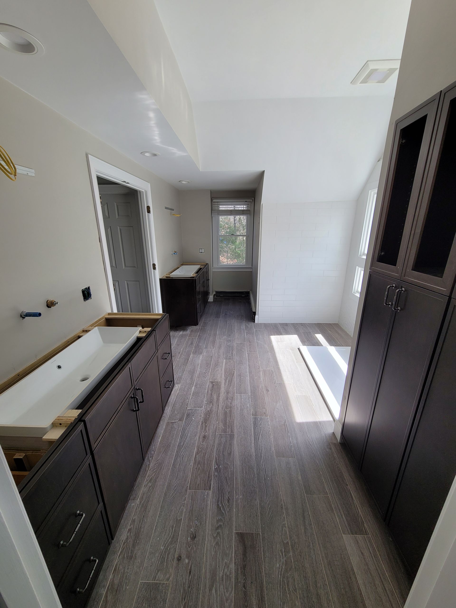 A bathroom with a sink , cabinets , and a window.