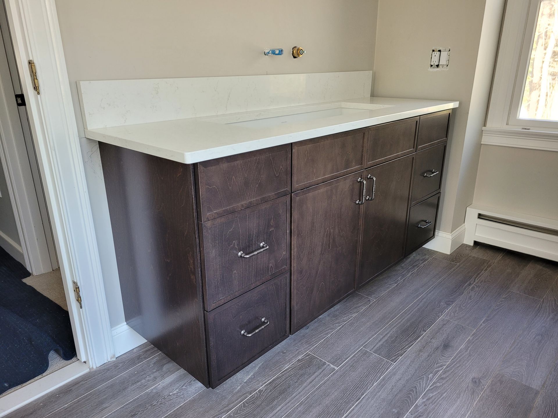 A bathroom vanity with brown cabinets and a white counter top.