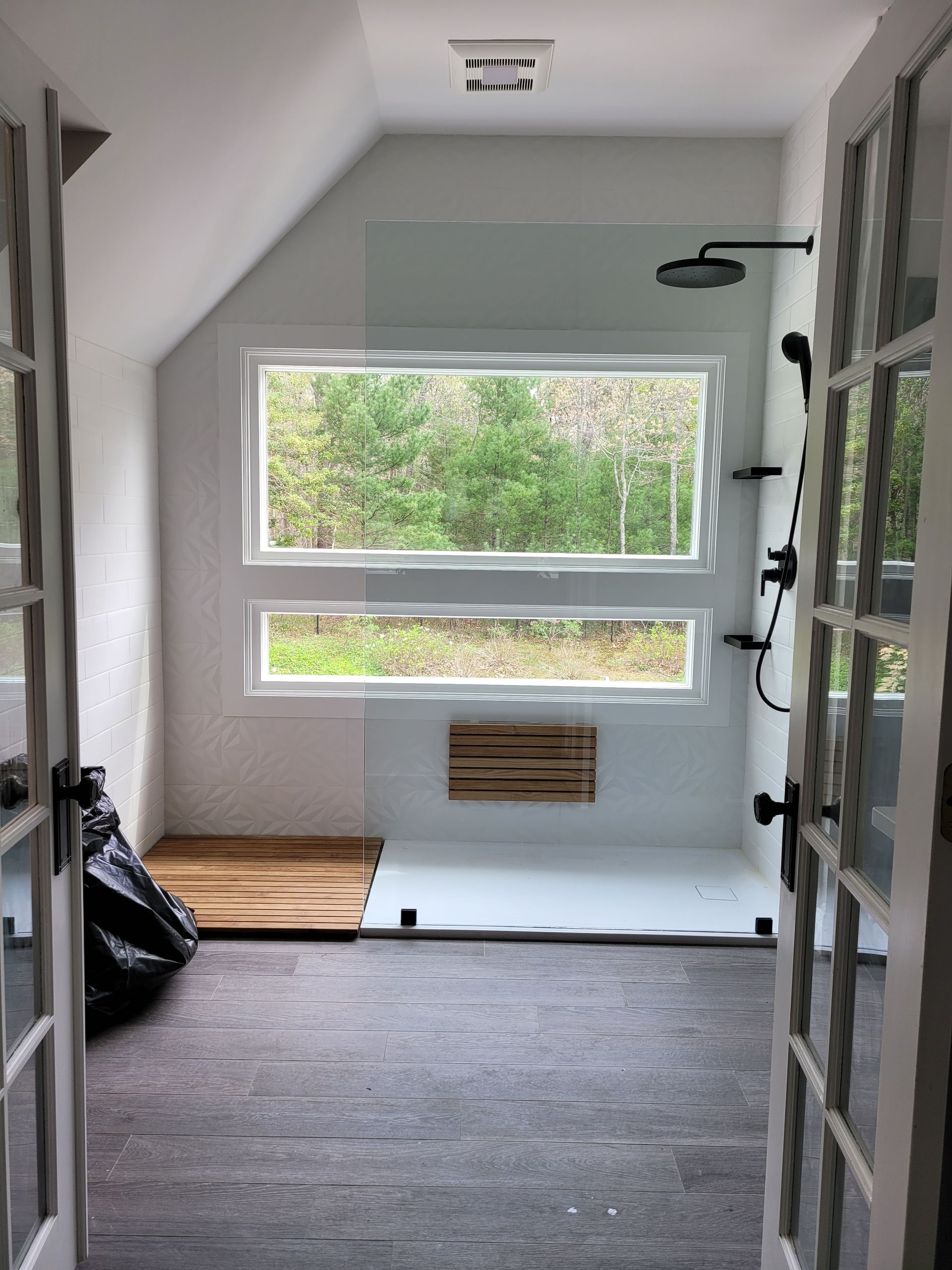 A bathroom with a walk in shower and a window.