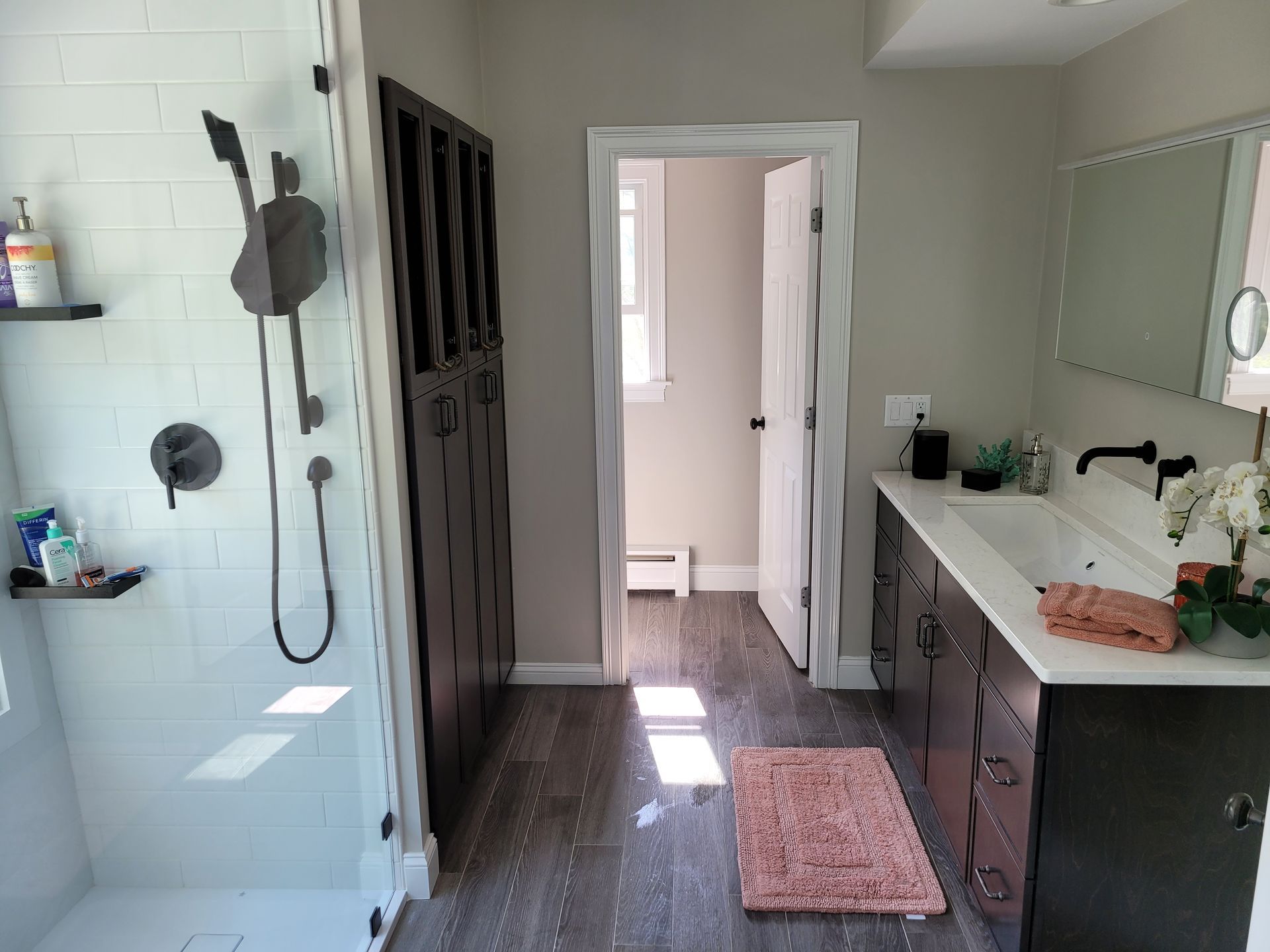 A bathroom with a walk in shower , sink and mirror.