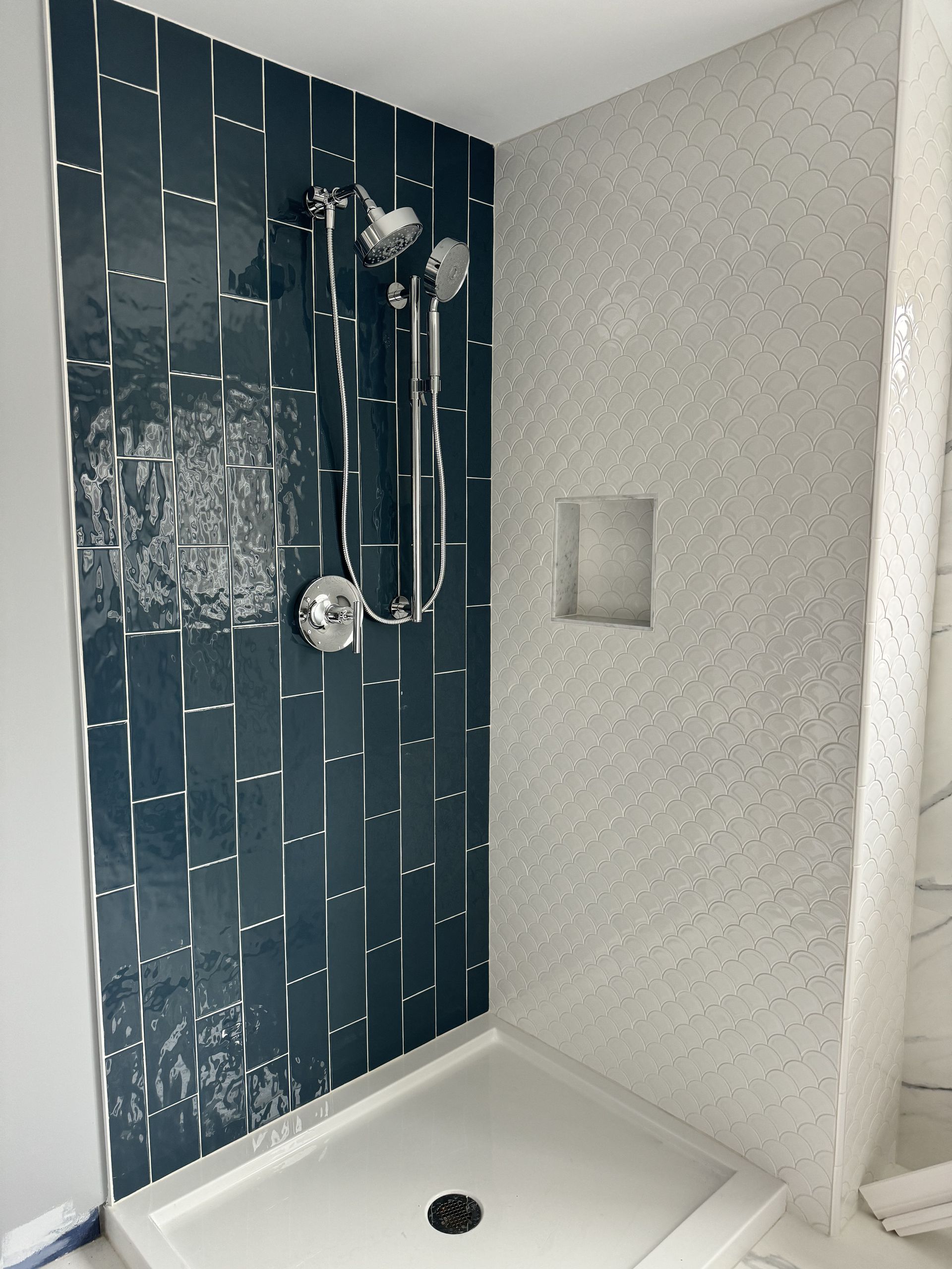 A shower with a blue tile wall and a white shower tray