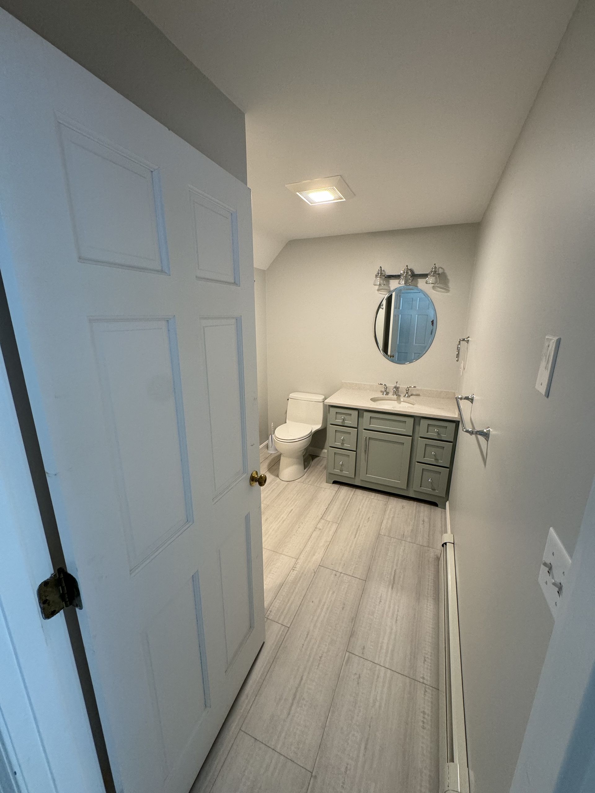 A bathroom with a toilet , sink , and mirror.