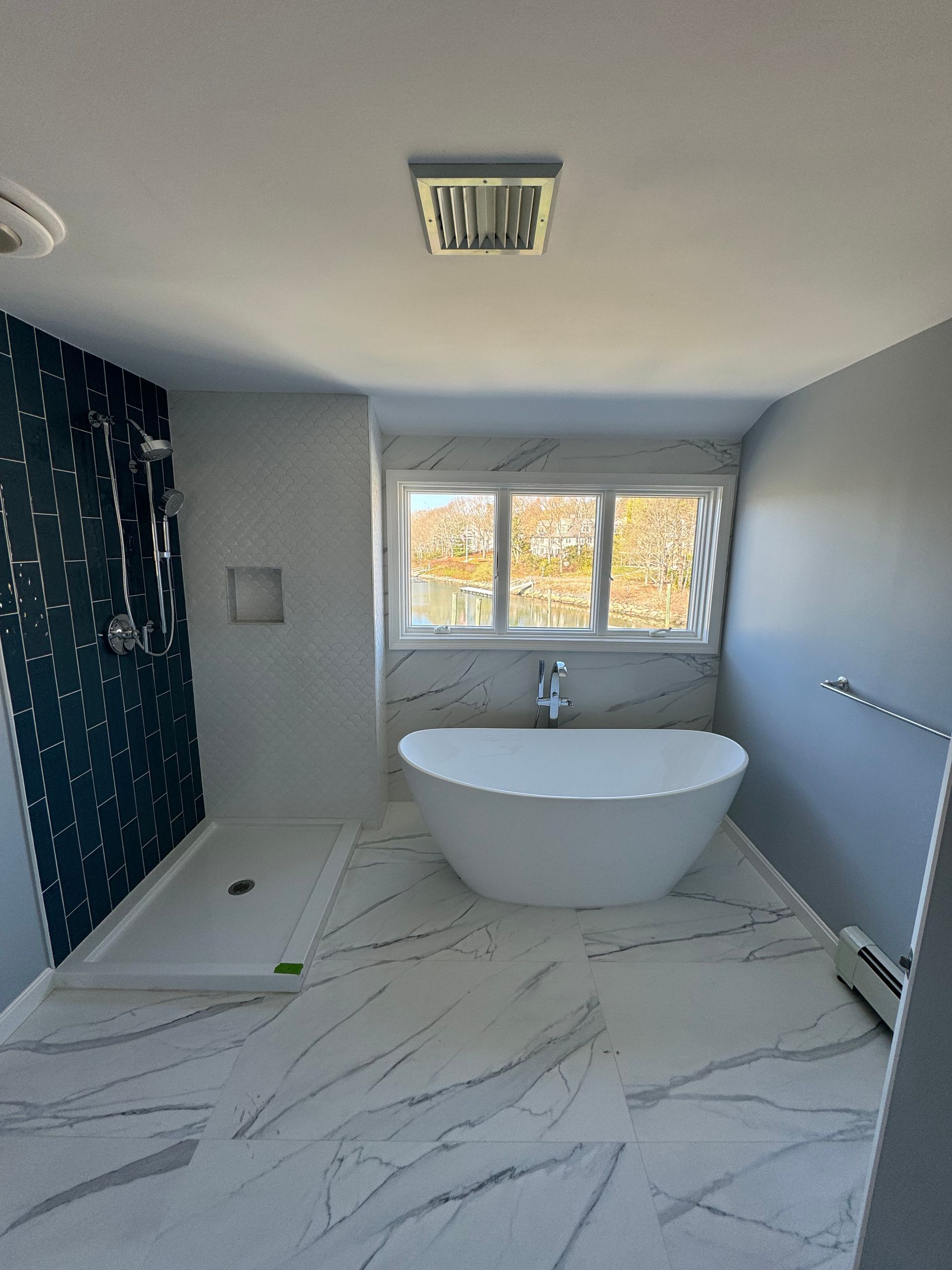 A bathroom with a tub , shower and window