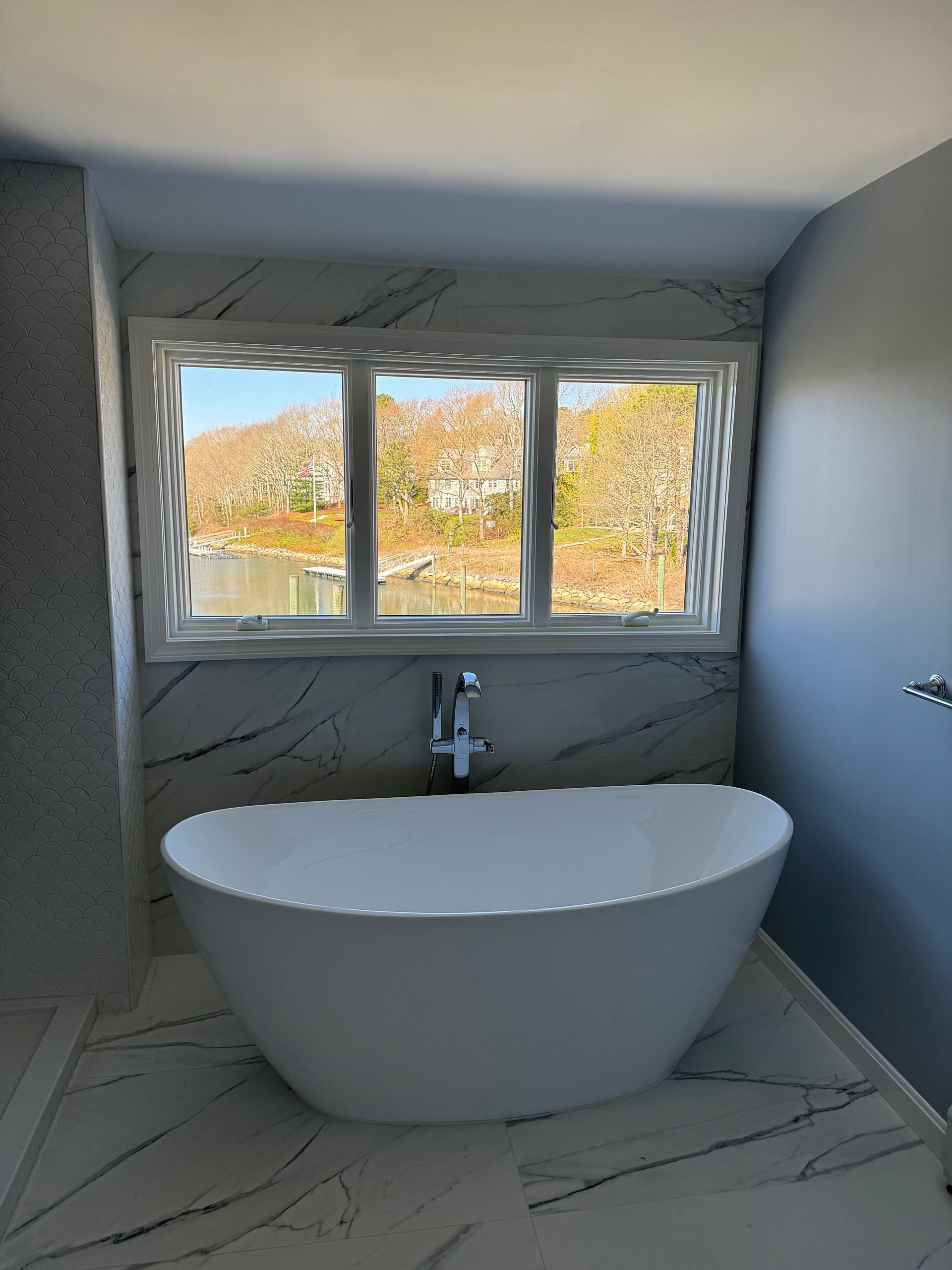 A bathtub in a bathroom next to a window