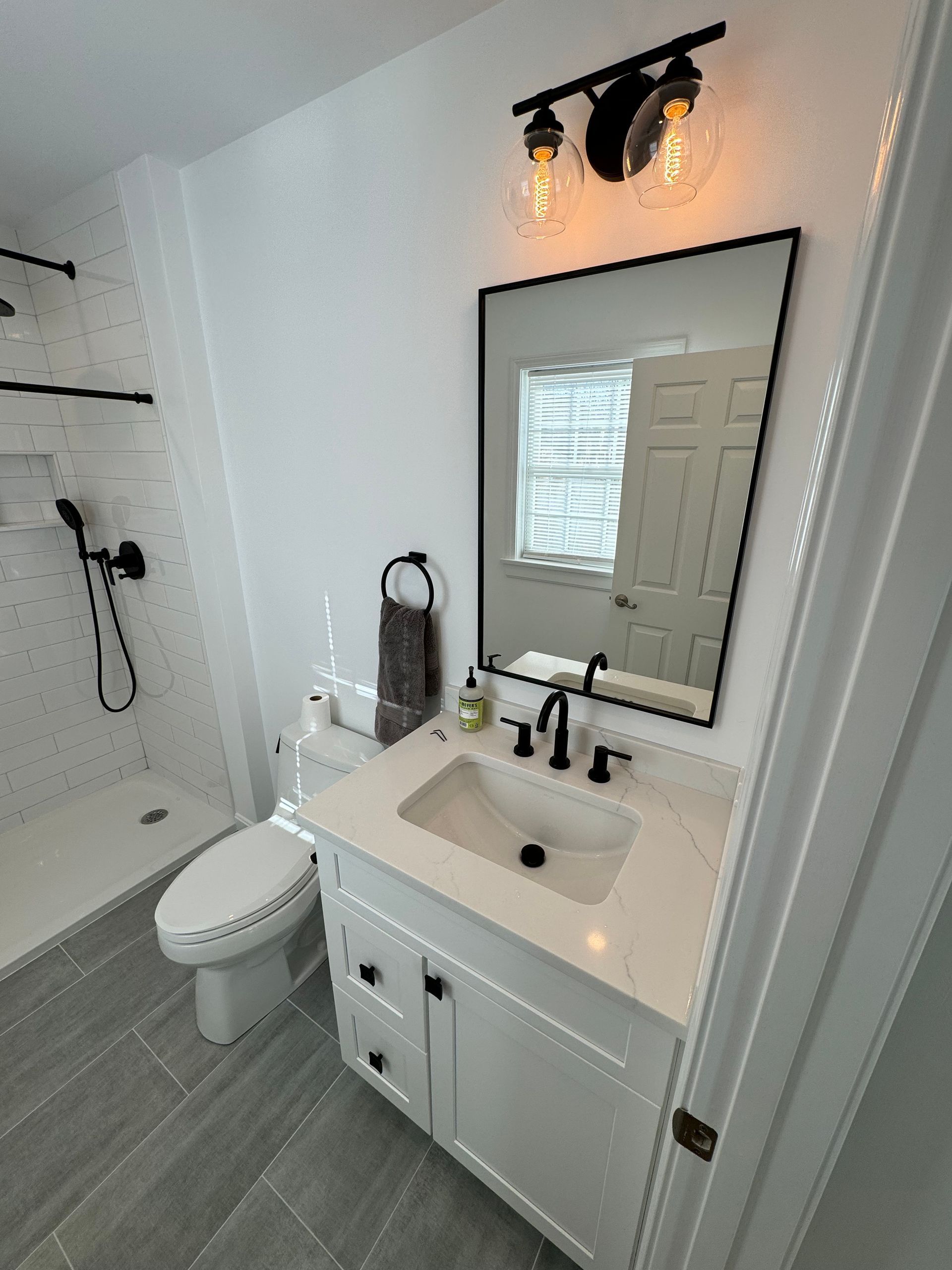 A bathroom with a toilet , sink , mirror and shower.