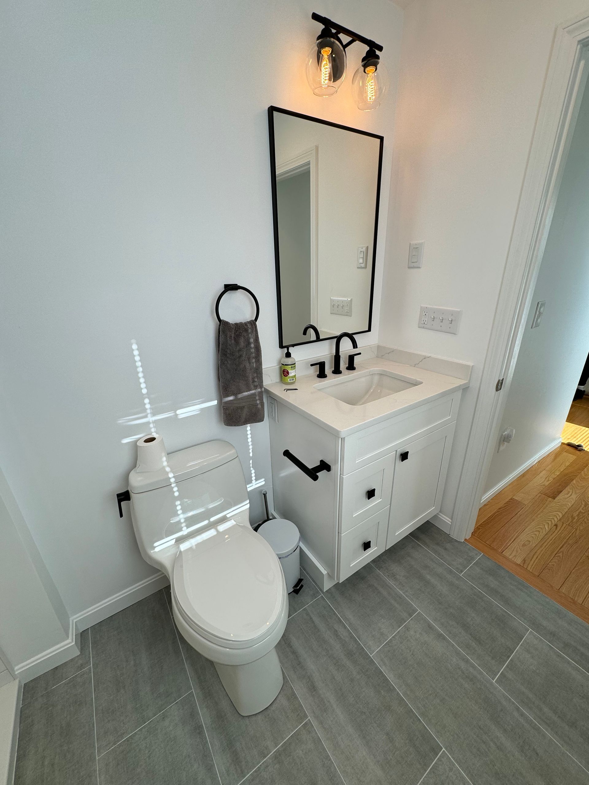 A bathroom with a toilet , sink and mirror.