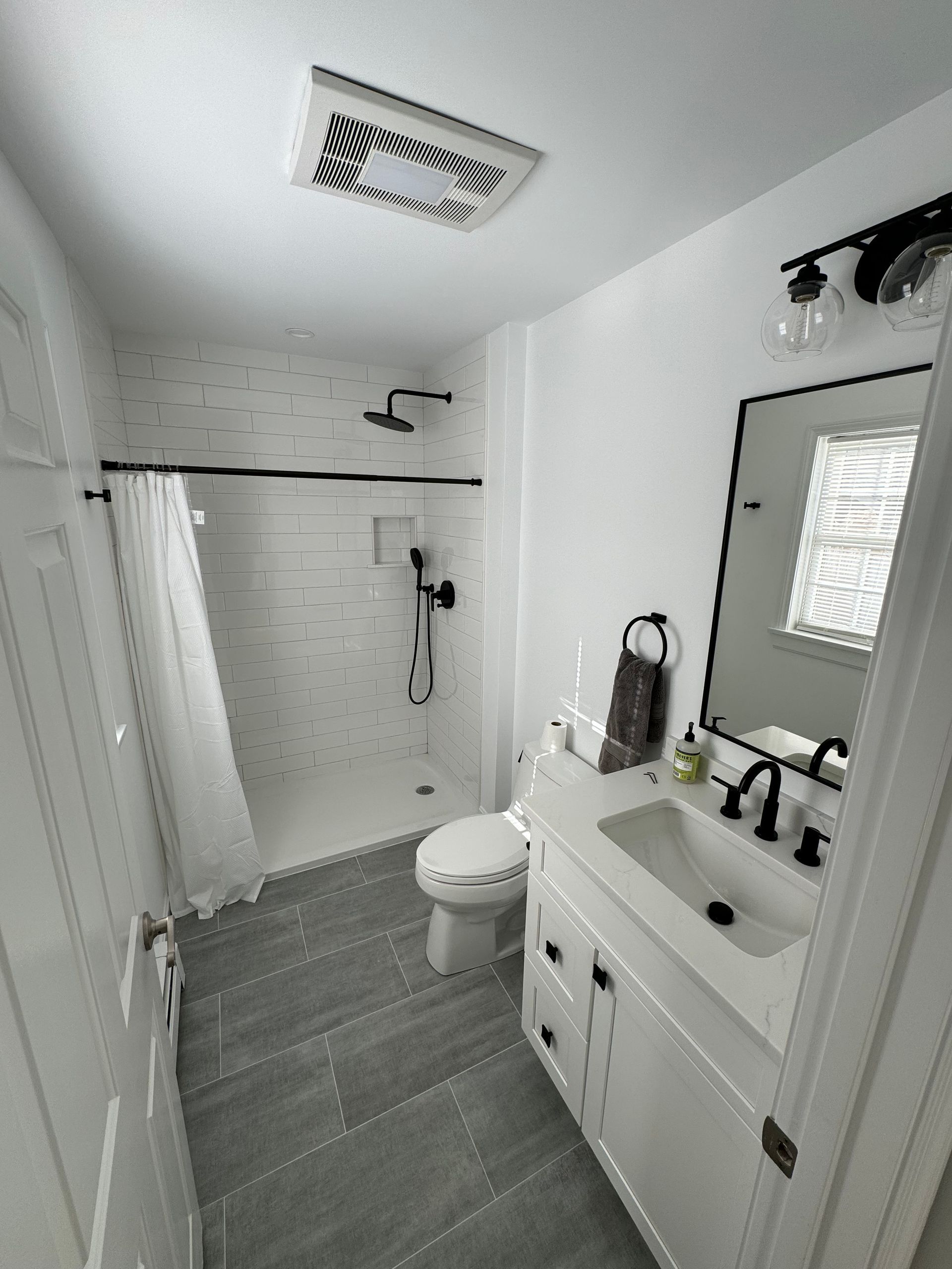A bathroom with a toilet , sink , shower and mirror.