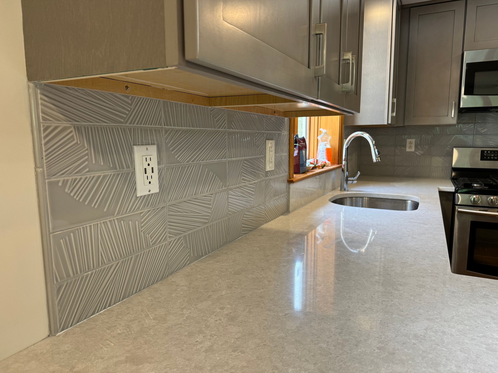 A kitchen with a sink , stove , microwave and cabinets.