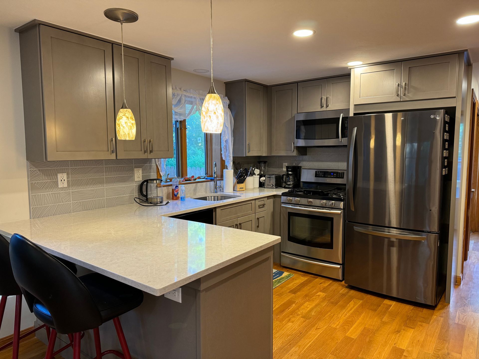 A kitchen with stainless steel appliances and gray cabinets.