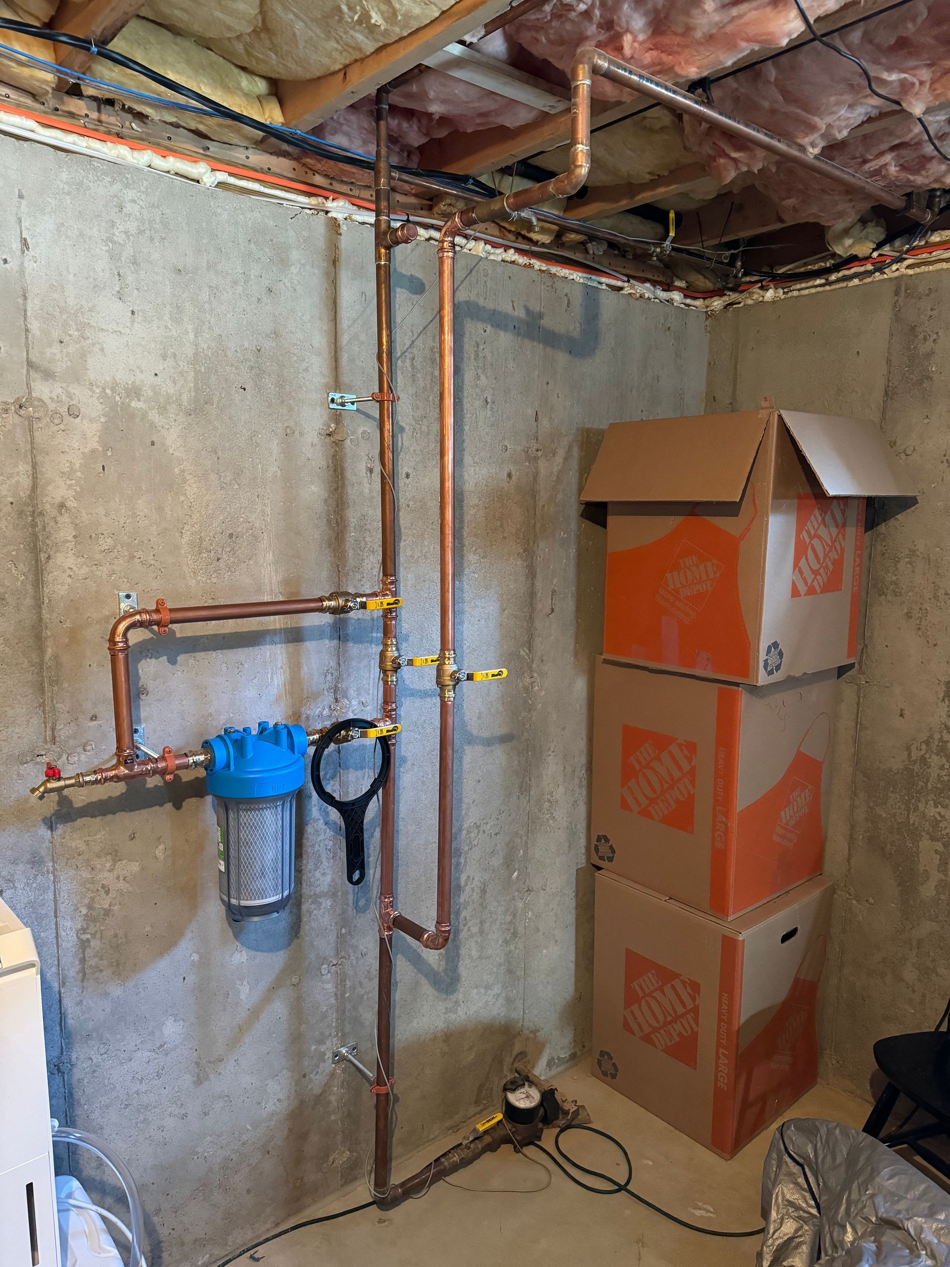 A room with boxes stacked on top of each other and copper pipes.
