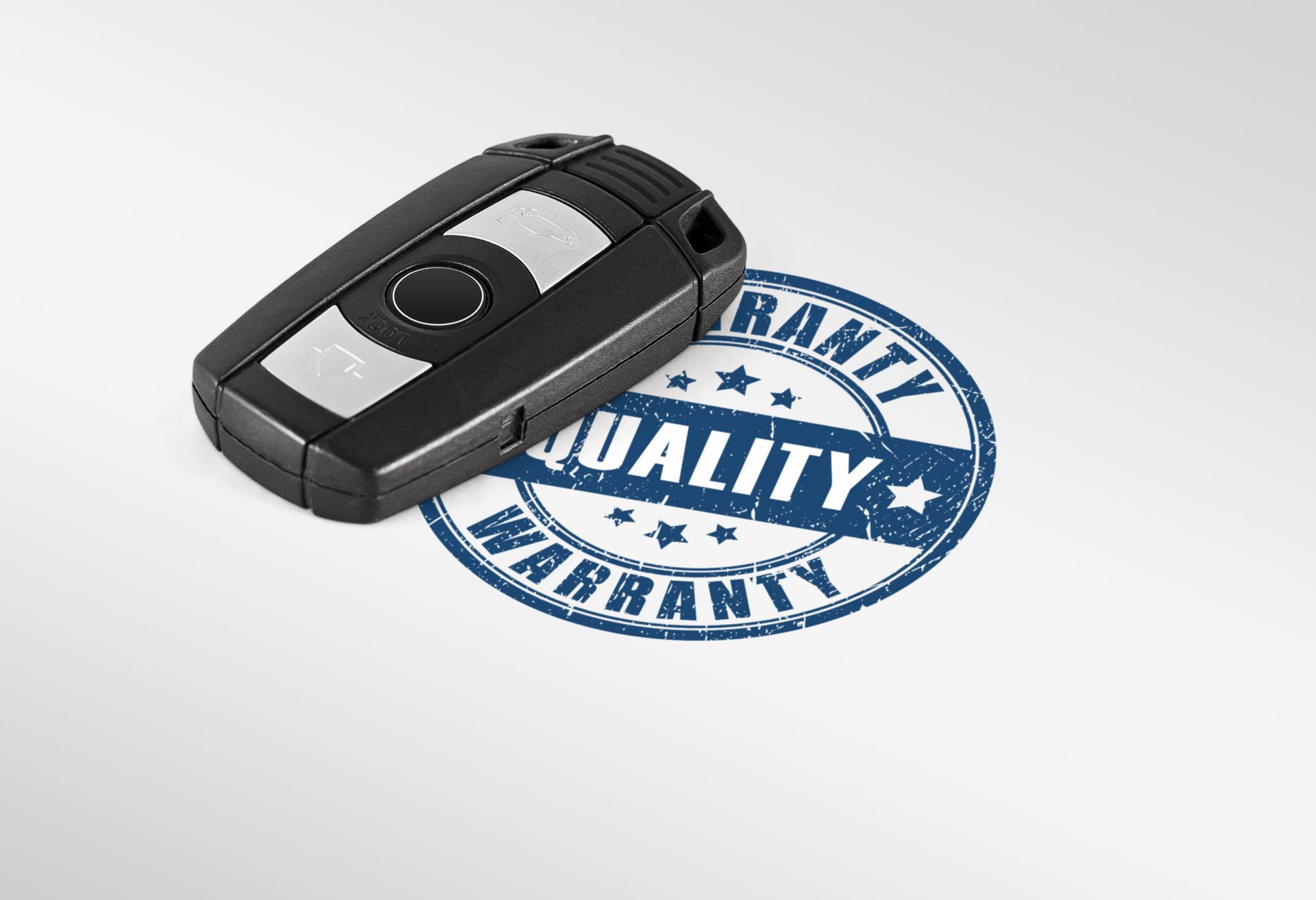 A black car key fob rests next to a circular blue (Quality Warranty) stamp on a white background.