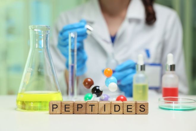 Laboratory scene with peptide molecules, glassware, and a scientist in blue gloves