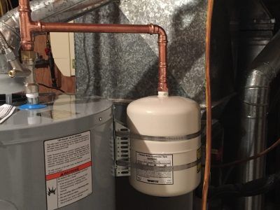 Copper piping connected to a white cylindrical water filtration tank in a utility room