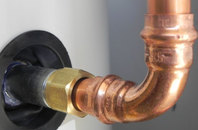 Copper plumbing pipe connected to a wall fitting with a black rubber seal