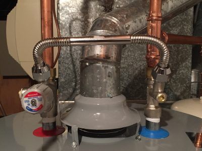 Water heater with flexible gas line and hot/cold pipes under a sink or utility area.