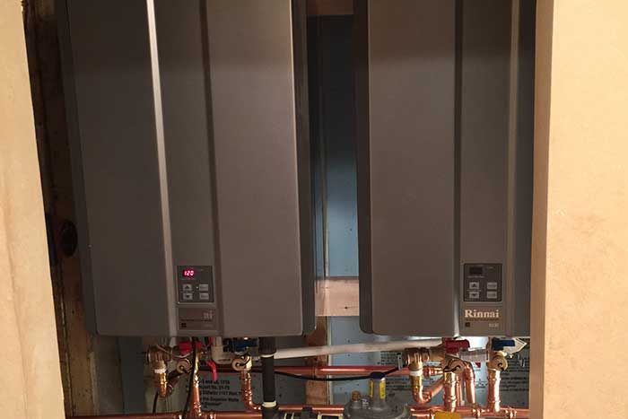 Two wall-mounted HVAC units with exposed copper piping and wiring underneath.