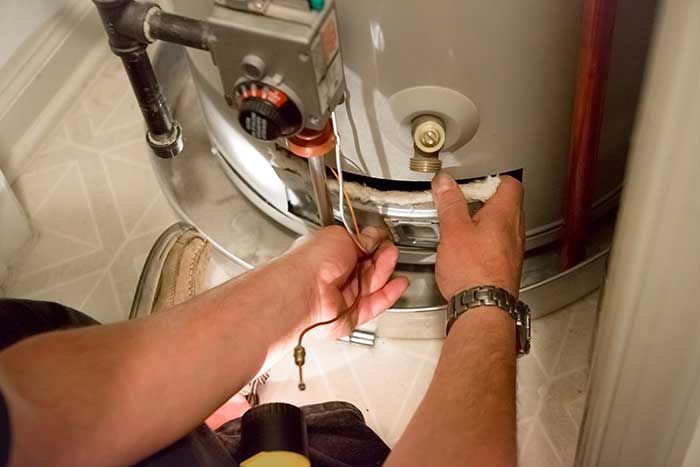 Hands adjusting a valve on a stainless steel tank with a wrench in an industrial setting