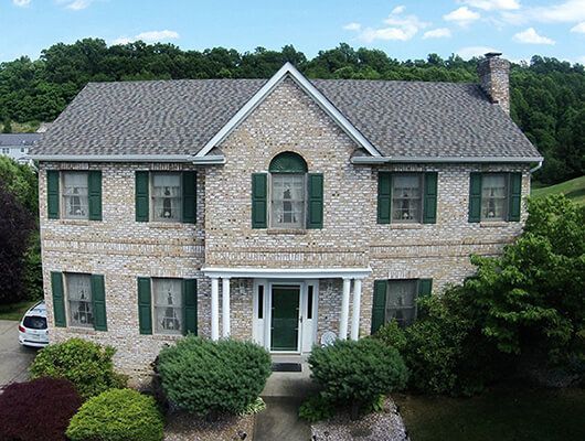 A large brick house with green shutters and a gray roof