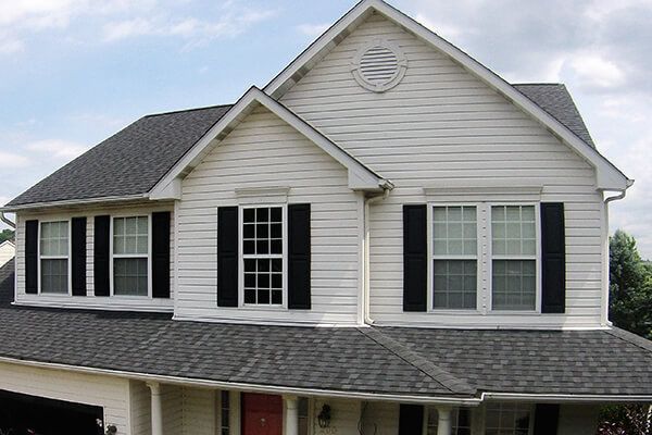 A white house with black shutters and a gray roof