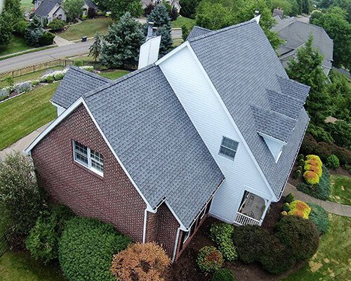An aerial view of a large brick house with a gray roof.