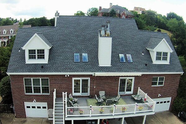 An aerial view of a large brick house with a large deck