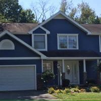 A large blue house with white trim and a garage.