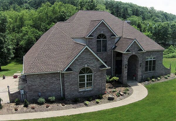 An aerial view of a large brick house surrounded by trees and grass.