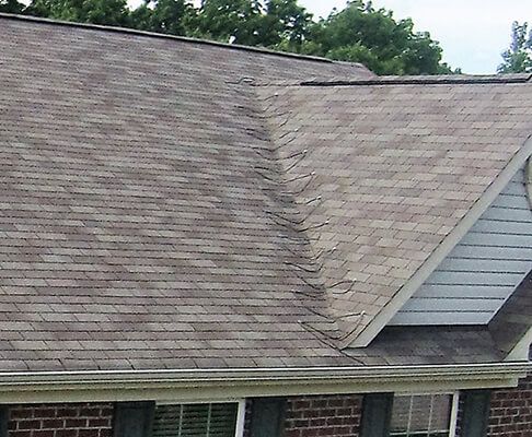 A brick house with a roof that has shingles on it