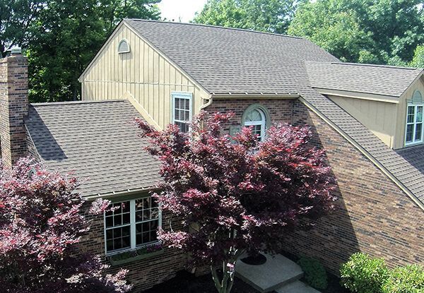 An aerial view of a brick house with a purple tree in front of it.