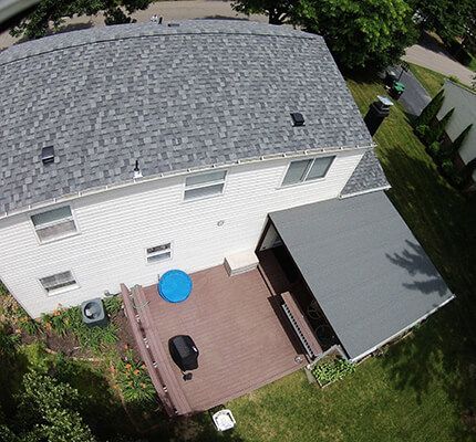 An aerial view of a house with a green siding and a gray roof.