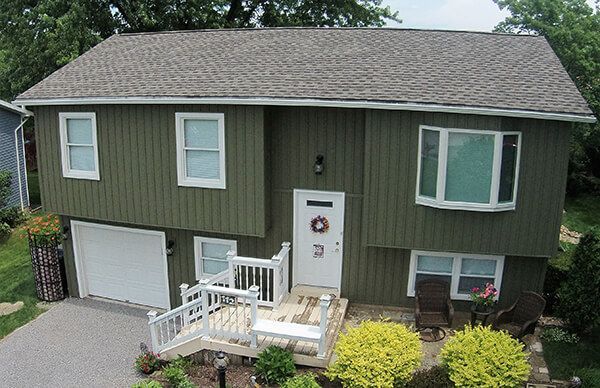 An aerial view of a house with a green siding and a gray roof.