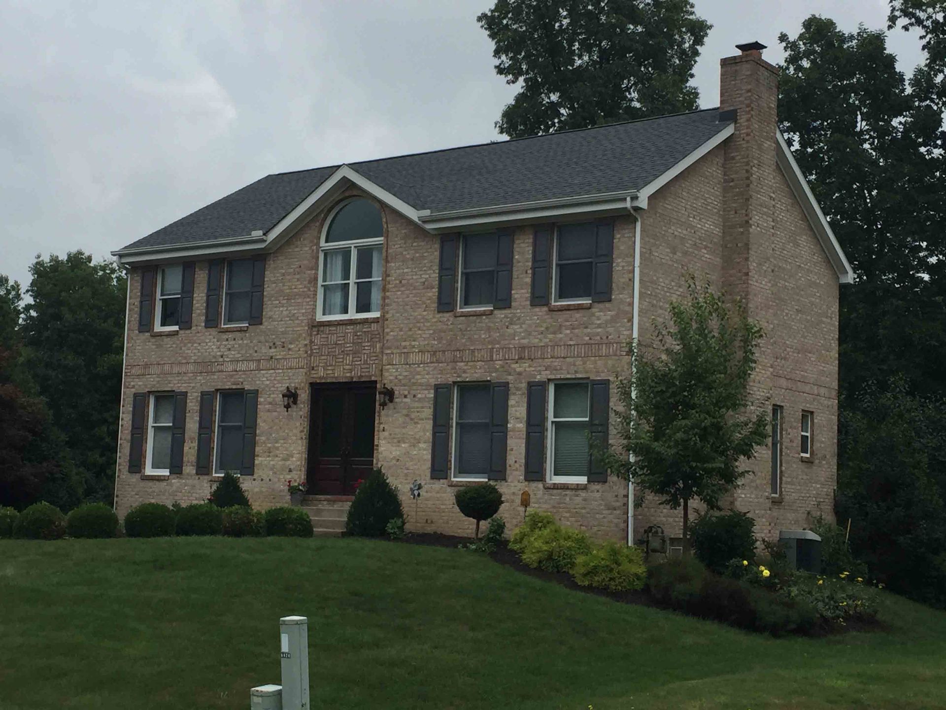 A large brick house with a lot of windows and shutters