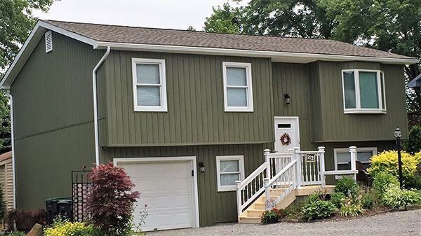 A green house with white trim and a white garage door.