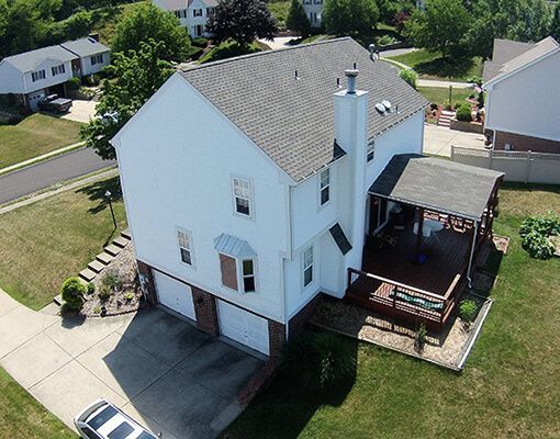 An aerial view of a large white house in a residential neighborhood.