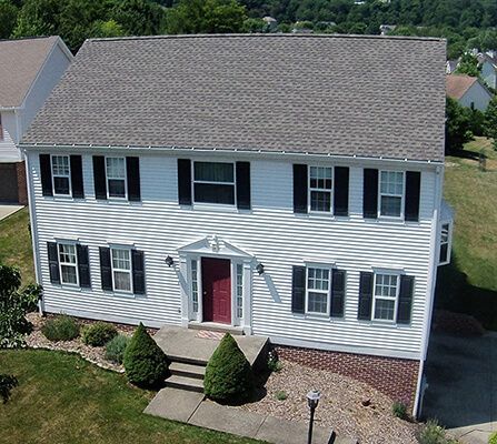 An aerial view of a white house with black shutters