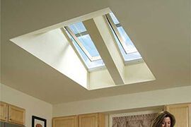 A woman is standing in a kitchen under a skylight.
