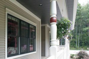 A porch with a white railing and a red pillar.