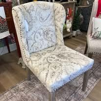 Upholstered chair with a light paisley pattern. Chair has tall back with nailhead trim.