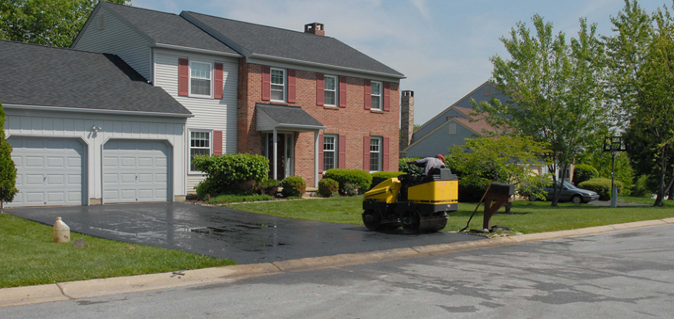 A large brick house with a driveway being paved in front of it.