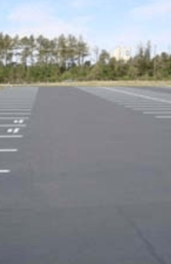 An empty parking lot with trees in the background.