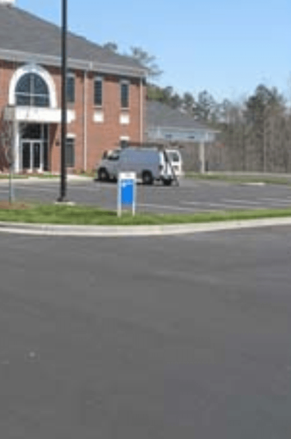 A white van is parked in front of a brick building