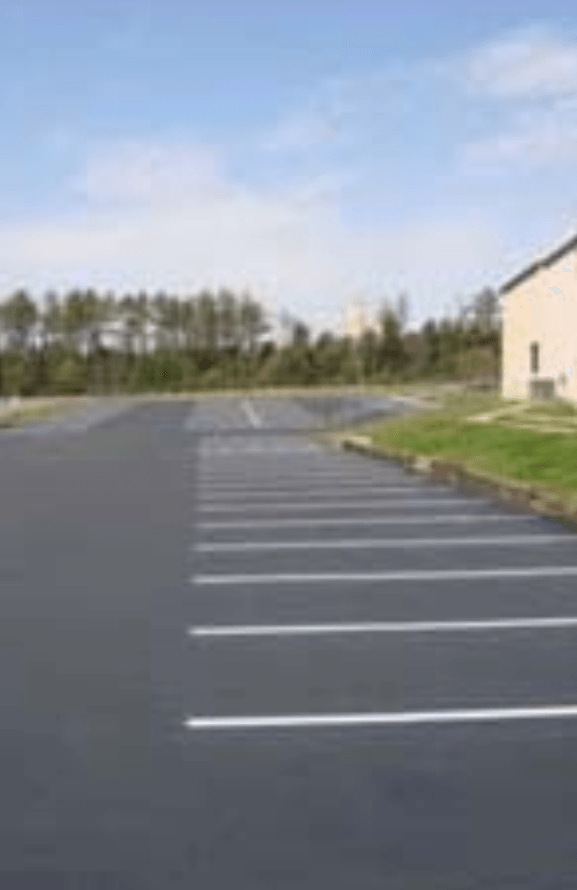 A parking lot with a building in the background on a sunny day.