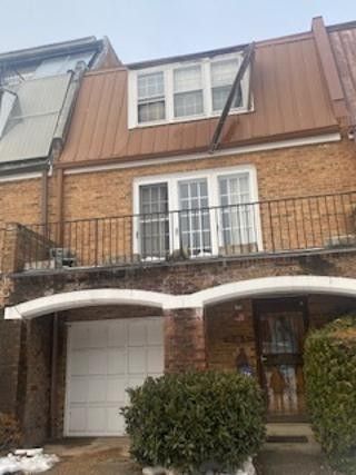 Brick townhouse with white garage door, balcony, and arched front porch windows