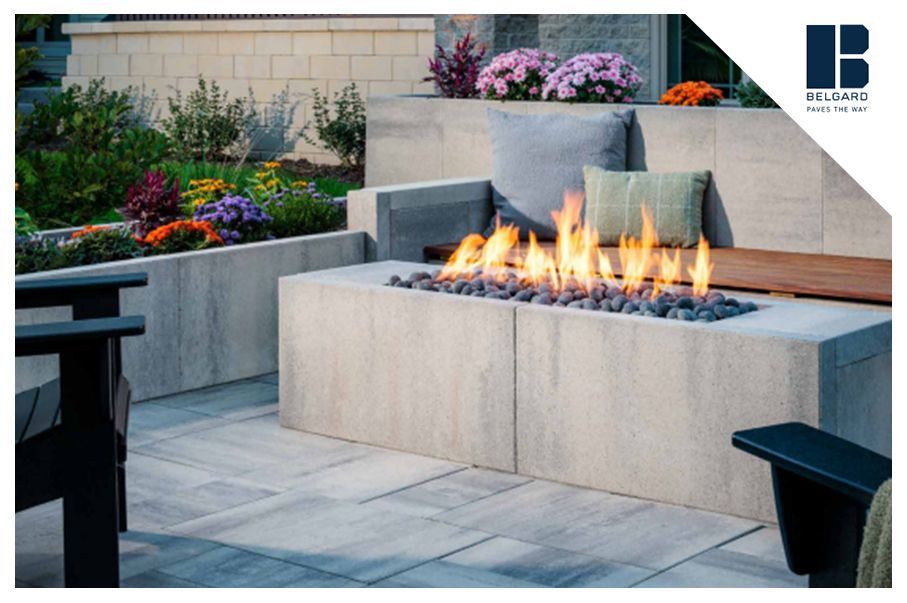 Outdoor patio with a concrete fire pit, seating, and landscaping.